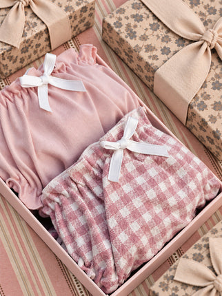 Pink and gingham frilled knickers with white ribbon bows in an open gift box.