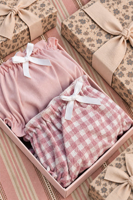Pink and gingham frilled knickers with white ribbon bows in an open gift box.